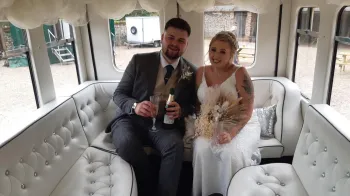 Bride and Groom holding a glass of champagne seating inside the Asquith Bus