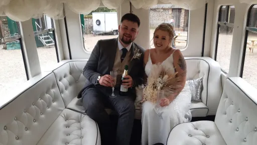Bride and Groom holding a glass of champagne seating inside the Asquith Bus