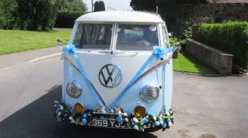 Full front view of classic VW campervan with blue ribbons and bows and flower decoration