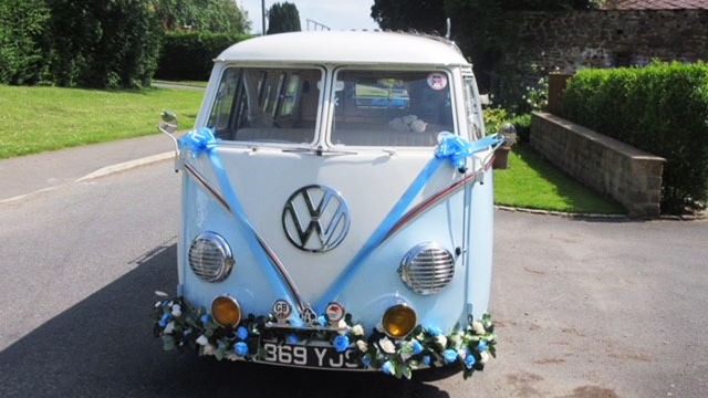 Full front view of classic VW campervan with blue ribbons and bows and flower decoration