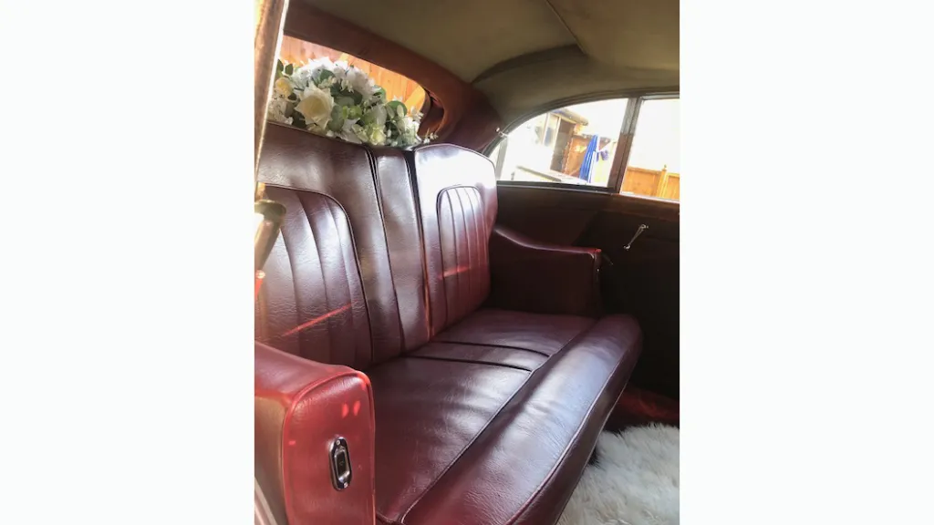 red leather rear seats inside rolls-royce with wedding flower decoration on rear parcel shelf