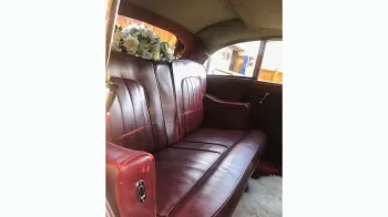red leather rear seats inside rolls-royce with wedding flower decoration on rear parcel shelf
