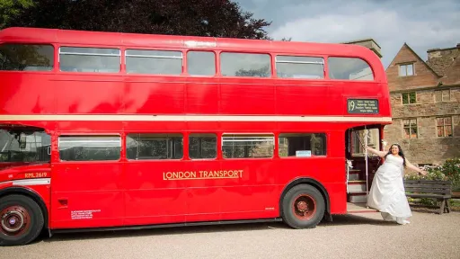 Bride wearing a white dress standing on the rear open platform of a Red Routemaster bus