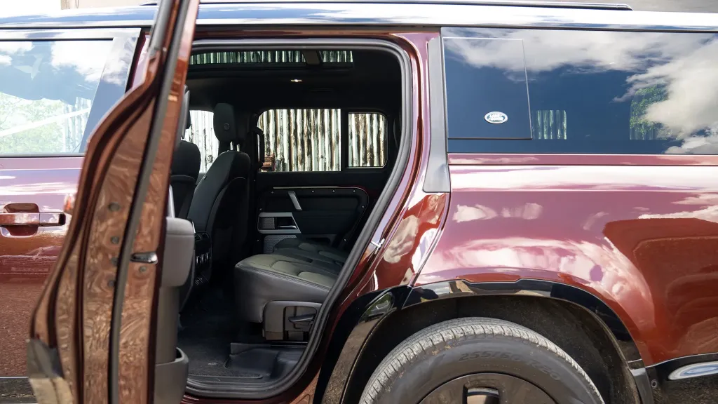 Rear left door open of a modern Land Rover Defender showing Black Leather interior
