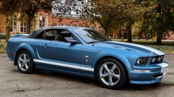 Right side view of Convertible Mustang in Blue with white stripes and roof up