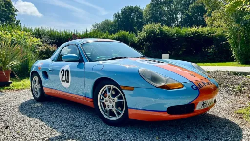Side view of Porsche Boxster Guld Livery in Light Blue and orange with chrome wheels