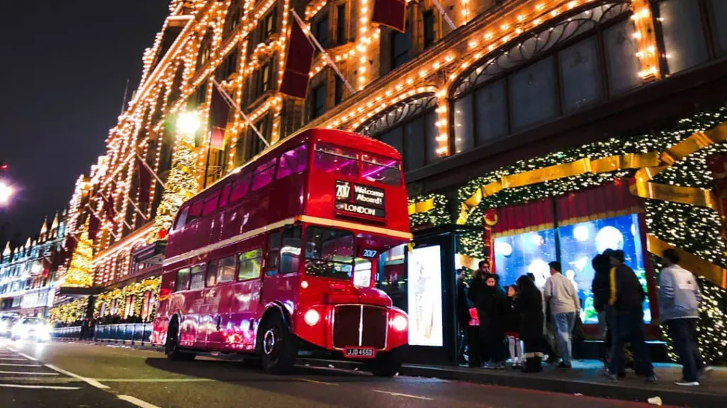 Big Red Double Decker London Routemaster Bus parked in the street of London illuminated with Christmas lights
