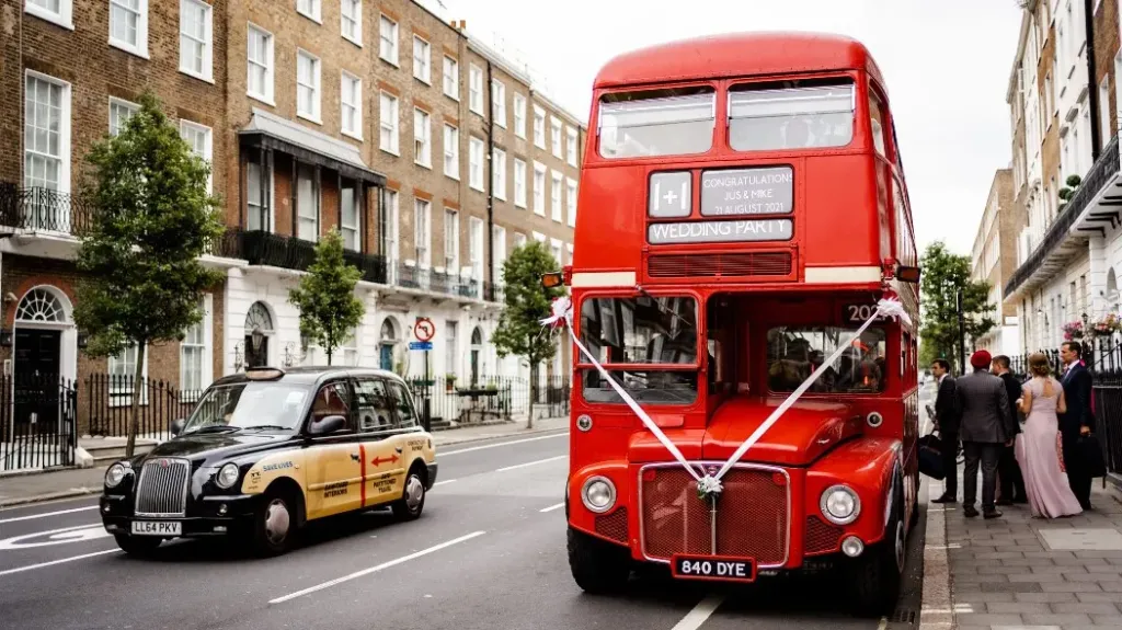 Red Double Decker Routemaster bus with white wedding ribbons parked in the London street
