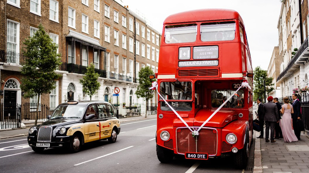 Red Double Decker Routemaster bus with white wedding ribbons parked in the London street