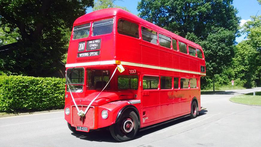 Big Red Doubl;e Decker Routemaster London Bus decorqated with white wedding ribbons
