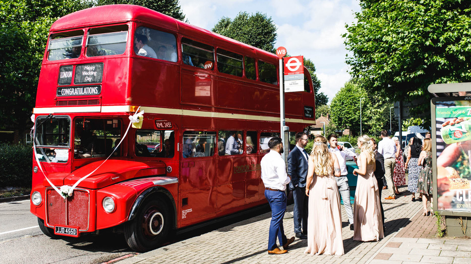 Double Decker Vintage Red Bus parked on the street of London with wedding Guests boarding the bus
