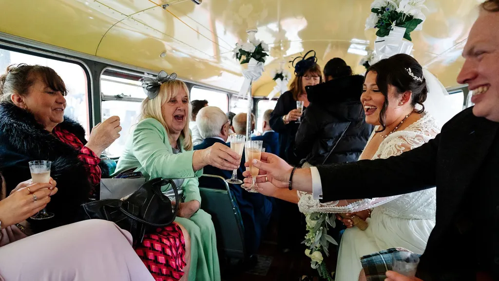 Wedding guests having a celebration toast inside a vintage routemaster wedding bus
