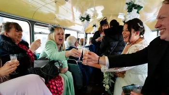 Wedding guests having a celebration toast inside a vintage routemaster wedding bus