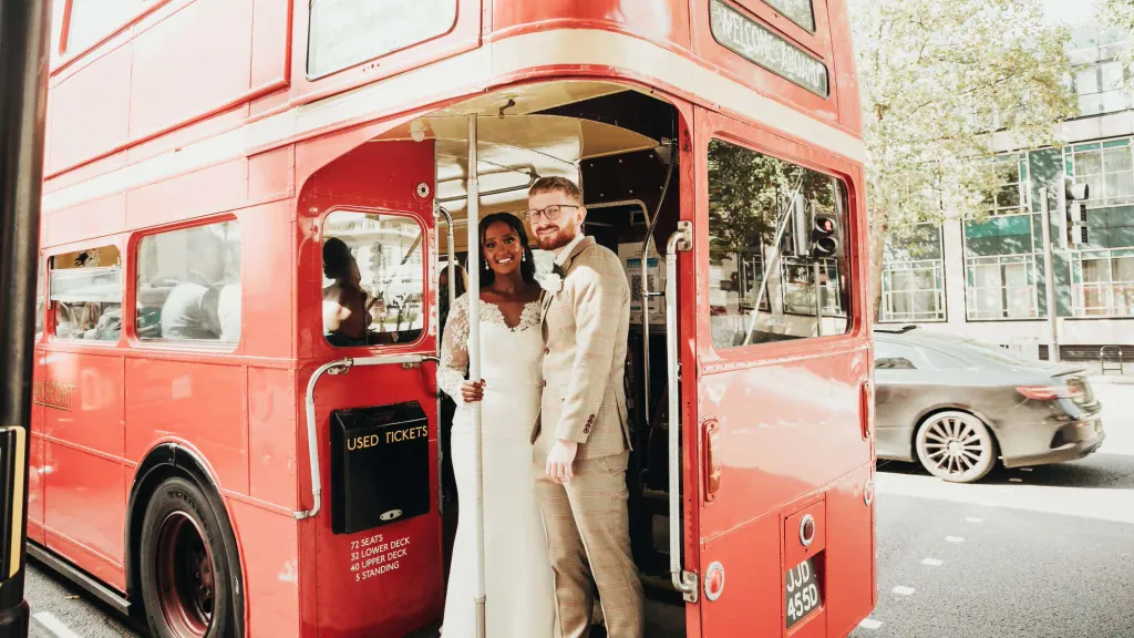 Bride and Groom standing on the rear open platform of an old Red London Routemaster Bus