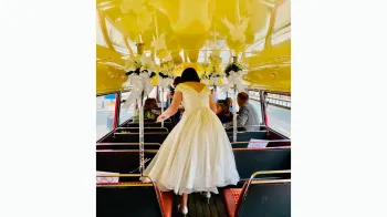 Bride wearing a large white wedding dress inside an old London Routemaster bus
