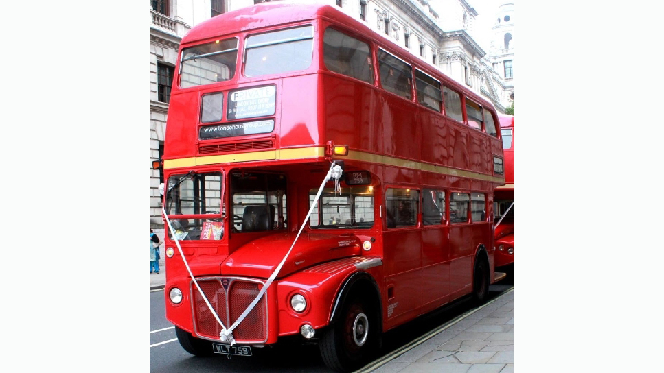 Front left view of Classic Red Routemaster London bus dressed with white ribbons