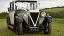 Frotn view of Vintage Car decorated with white ribbons parked in a green field