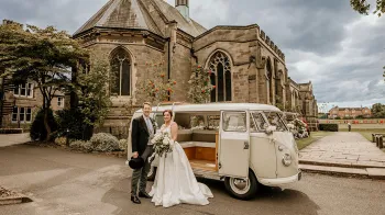 Bride and groom with a classic campervan and church in Background