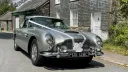 Silver aston Martin DB5 dressed with white ribbons across its bonnet and a white bow on its front grill