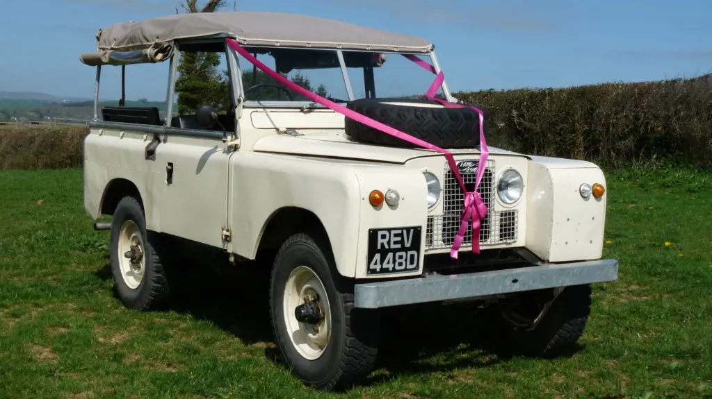 Classic Land Rover in Old English White decorated with pink wedding ribons and bows and side windows open
