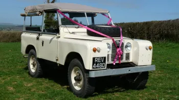 Classic Land Rover in Old English White decorated with pink wedding ribons and bows and side windows open