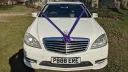 Front view of White Modern Mercedes with purple ribbons and bows