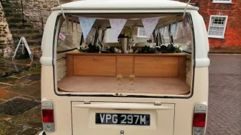 Rear view of classic VW Cqampervan with boot open showing a couple of champagne glassed