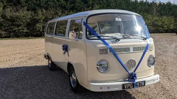 Front right side of a classic VW Campervan in cream and ivory dressed with blue wedding ribbons and bows