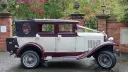 vintage Badsworth wedding car in Ivory with Burgundy wheel arches and roof wth black soft top roof close decorated with ivory ribbons and bows on door handles and rear black picnic trunk