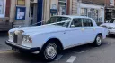 Left side view of classic Rolls-Royce decorated with white ribbons in the street of Swansea
