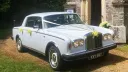 Classic Rolls-Royce silver shadow dressed with Ivory wedding ribbons, twin front head lights switched on parked in front of a church in Swansea