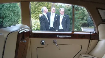 Photo taken frominside a classic Bentley looking at Groom and his two groomsmen through the window