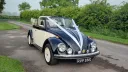 Classic Beetle in Ivory and Black with convertible roof open and dressed with White ribbons accros its black bonnet.