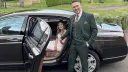 Groom opening the rear passenger side door to the Bride wearing a white dress