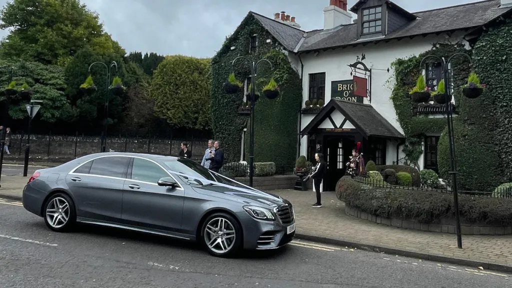 Mercedes with white ribbons parked in front of a wedding venue