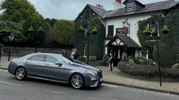 Mercedes with white ribbons parked in front of a wedding venue