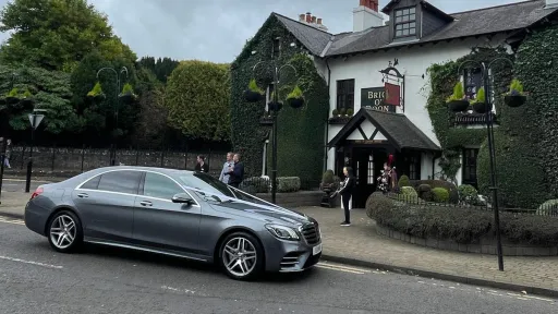 Mercedes with white ribbons parked in front of a wedding venue