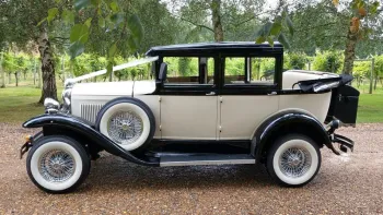 Left side view of a Badsworth Landaulette in Ivory with black wheel arches decorated with ribbons and convertible roof open