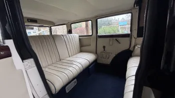 rear interior space inside Bramwith wedding car with royal blue carpet and cream leather bench seats