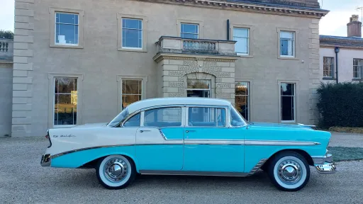 Right side view of American Chevrolet BelAir in Teal Blue and White parked outside wedding venue in Midlands