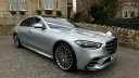 Right side view of silver Mercedes dressed with Ivory Ribbons parked in front of wedding venue