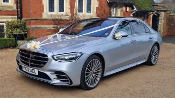 Silver Mercedes S-Class decorated with Ivory Wedding Ribbons and bows on front of venue in Bristol