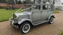 Front left view of Silver vintage imperial wedding car with soft top rear roof closed