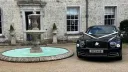 Dark Blue Bentley parked outside wedding venue with white ribbons and bows