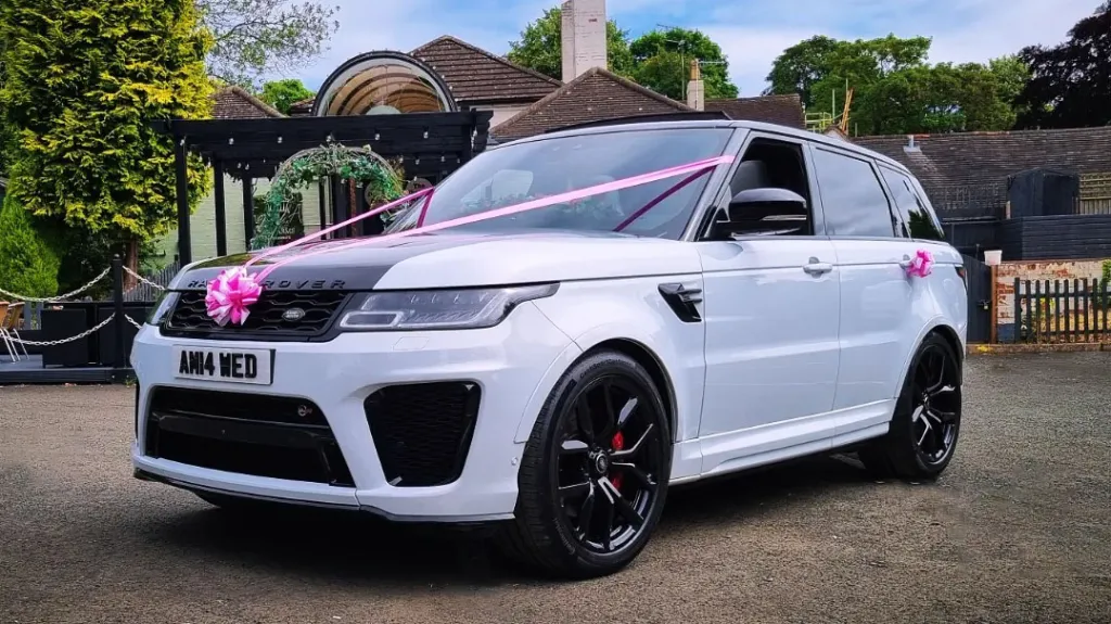 Front view of white Range Rover SVR with black alloy wheels and black carbon bonnet decorated with pink ribbons