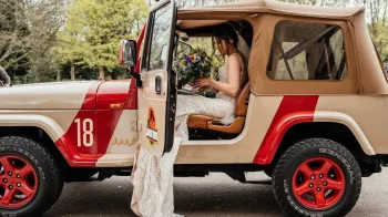 Bride wearing a white dress seating inside a Jeep Wrangler from the Jurassic Park movie