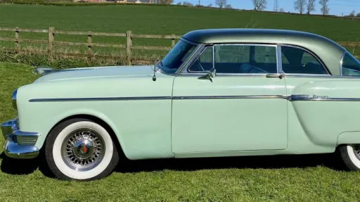 Left side view of a pale groom American Packard Super Clipper  with spokes chrome wheels and white wall tires
