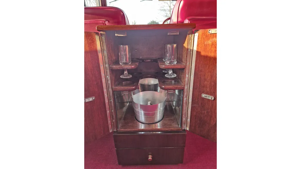 Vintage car interior wooden cabinet open showing a glass and bottle holder