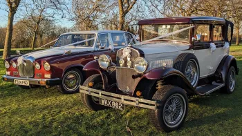 Two Matching Burgundy and White Wedding Cars. Right car is a vintage Badsworth and the left car is the Classic Daimler Limousine