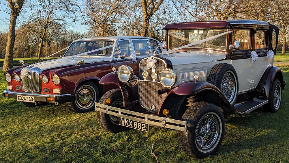 Two Matching Burgundy and White Wedding Cars. Right car is a vintage Badsworth and the left car is the Classic Daimler Limousine